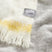 A close up of the grey ombre throw showing the subtle texture and fringe.