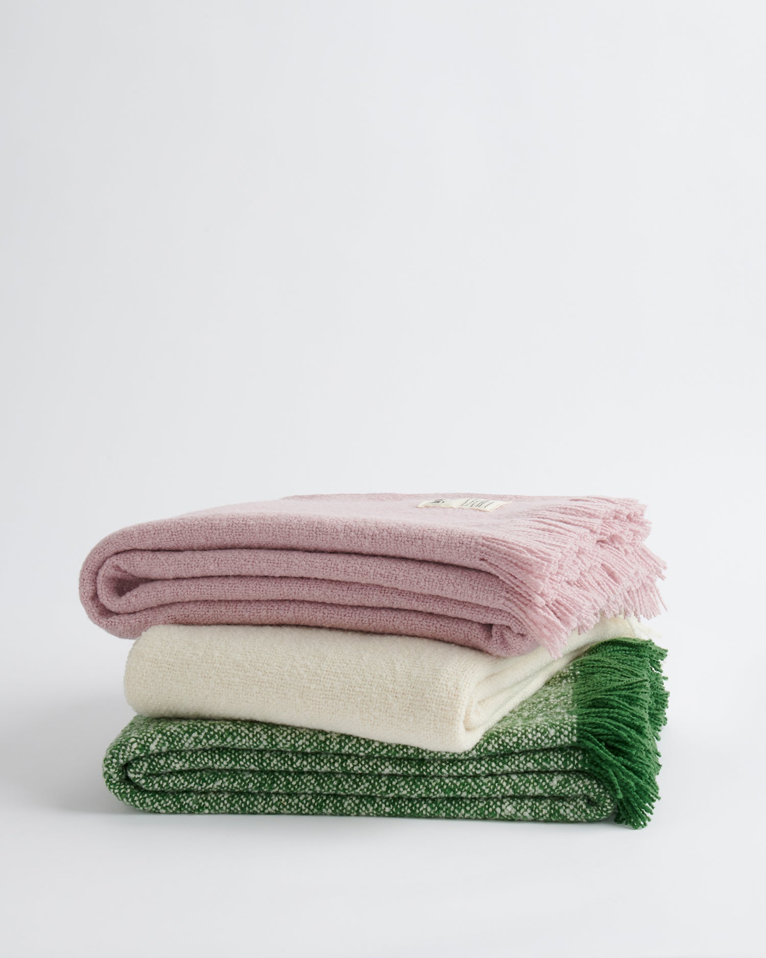 A stack of three cooper's cormo throws, one in each colour.