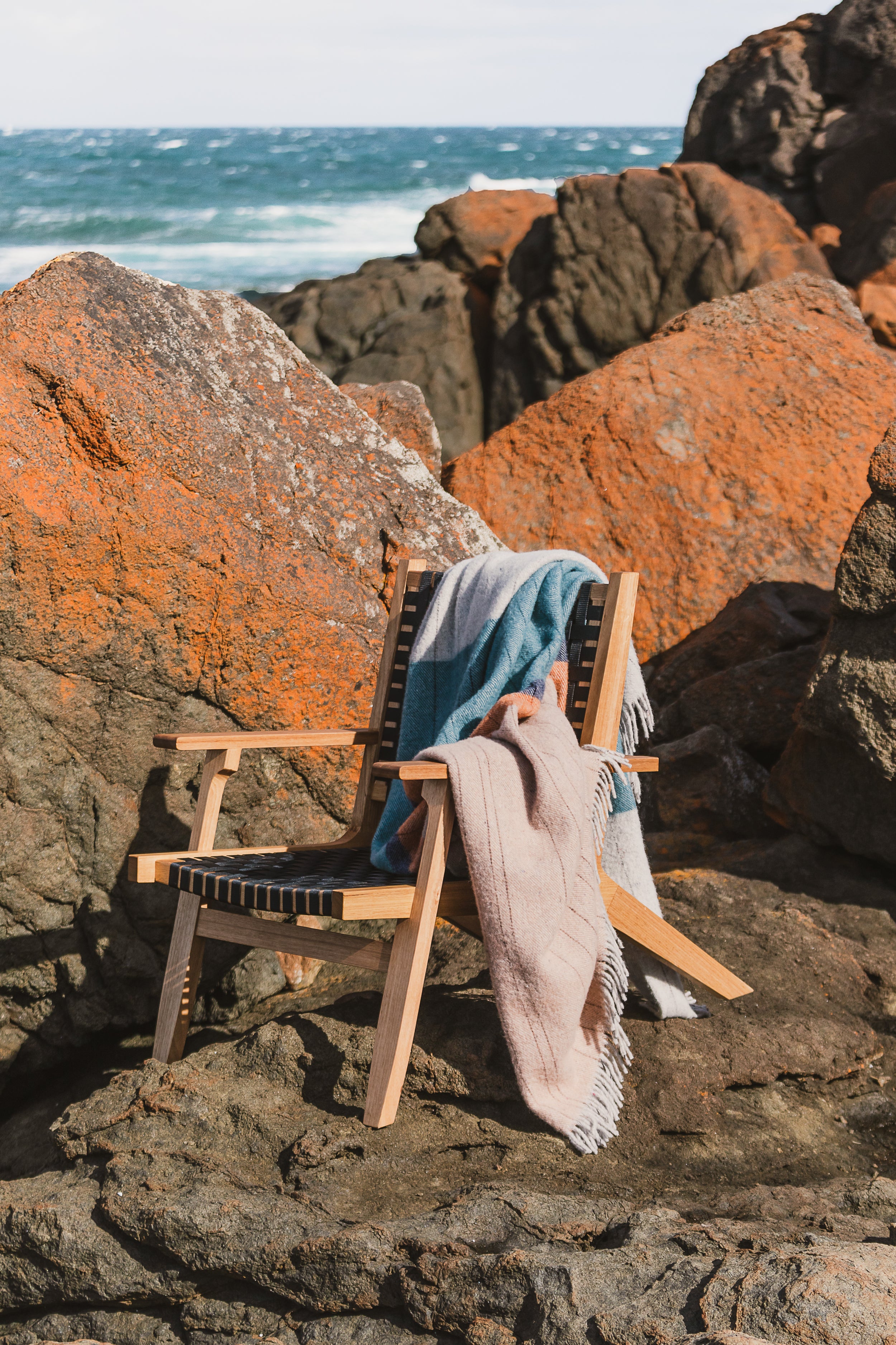 The Bay of Fires throw draped over a chair on the lichen covered rocks.