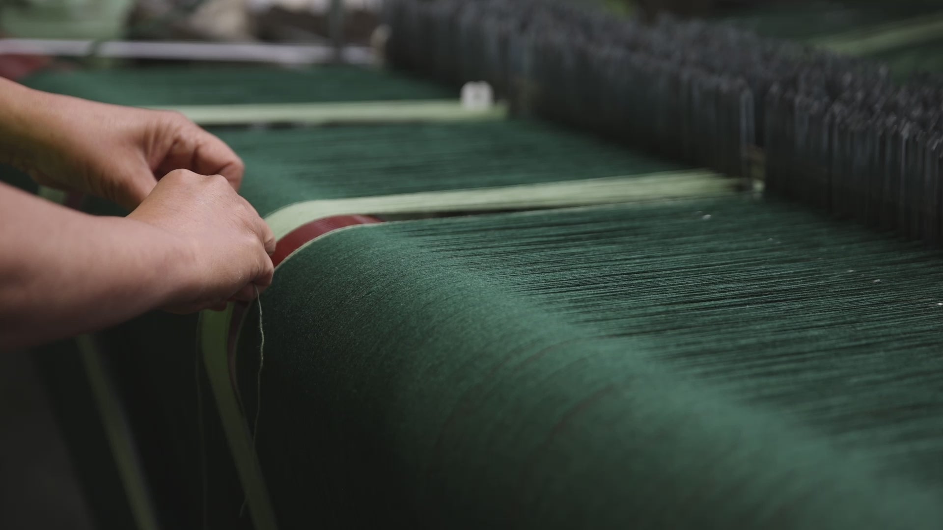 A video of a pair of hands tying in thread on the loom.