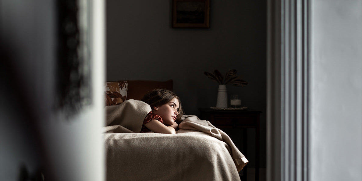 A girl laying on a bed made up with Waverley Mills blankets.