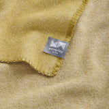 A close up of the corner of a opal geo blanket, featuring the woven twill pattern and whip stitched edge.
