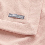 Close up merino wool baby blanket nest in cameo rose pink.