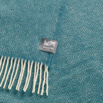 A close up of a teal knee rug with a diamond pattern.
