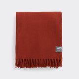 A folded essential throw in solid desert red.