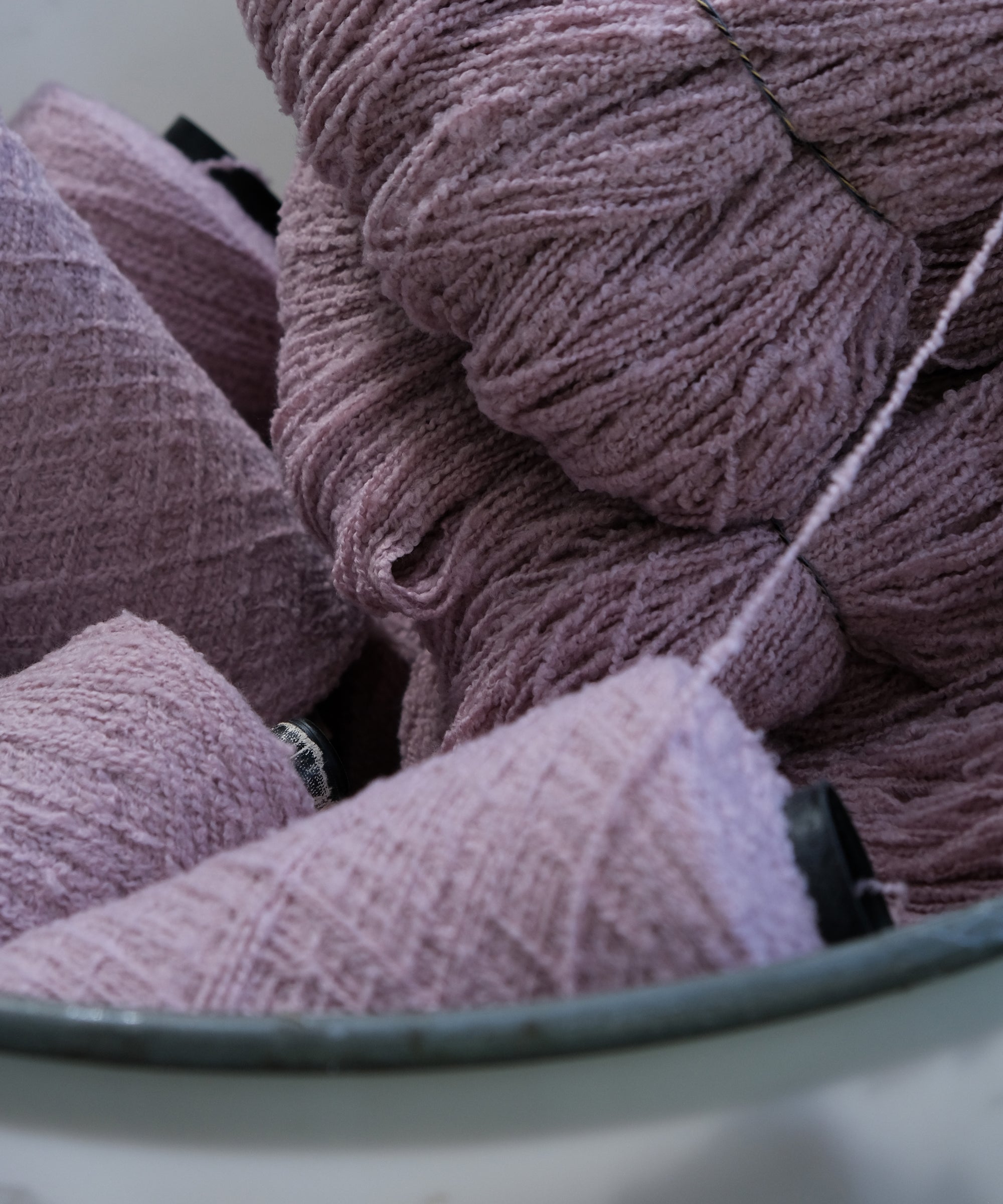 Mauve Cooper's cormo boucle yarn on cones.
