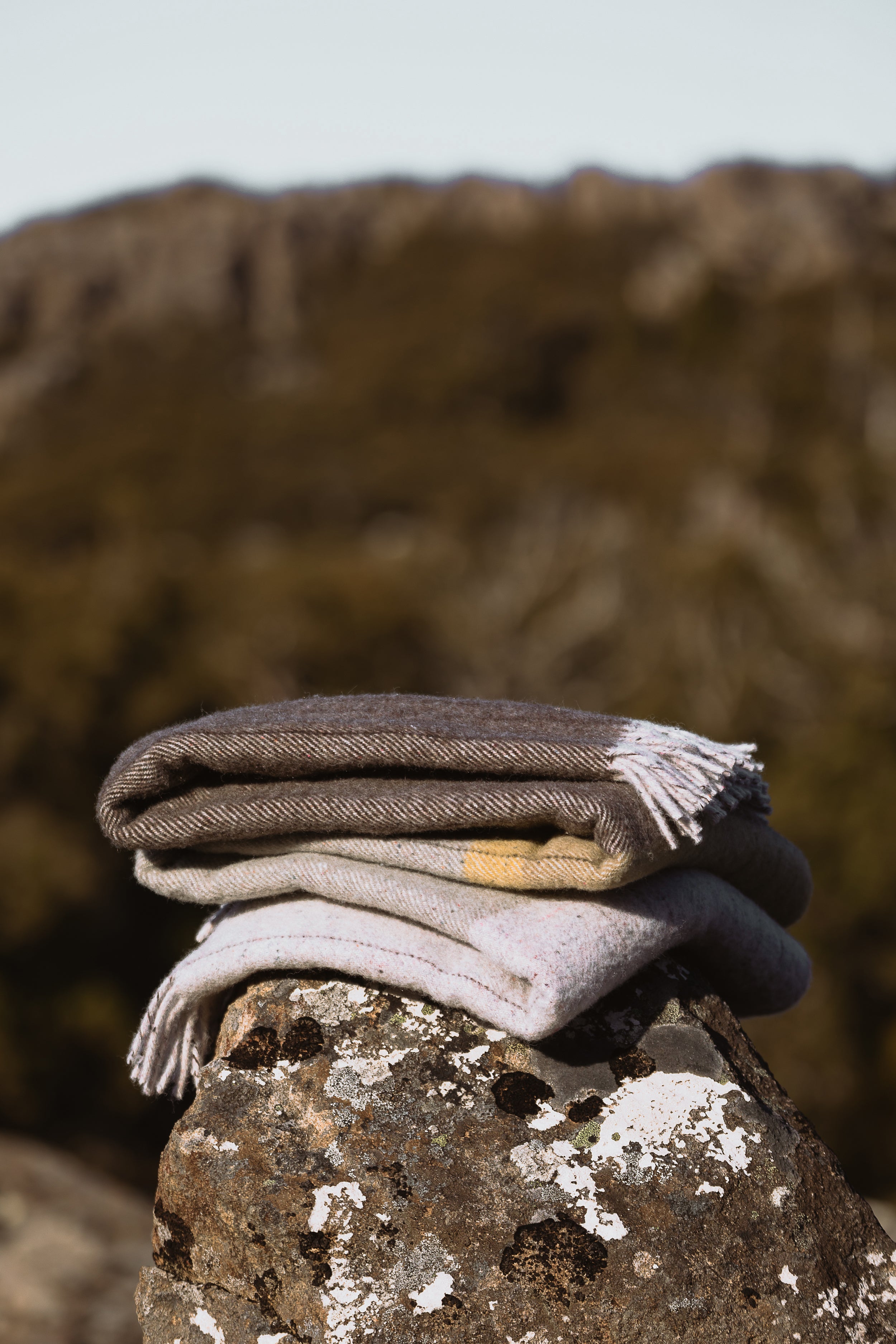 The Cradle Throw folded sitting on a lichen covered rock.