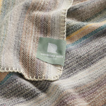 A close up of the ranger stripe blanket in earth showing the natural whip stitch edge.