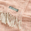 A close up of the loose weave of the shawl, showing the contrast natural coloured fringe.