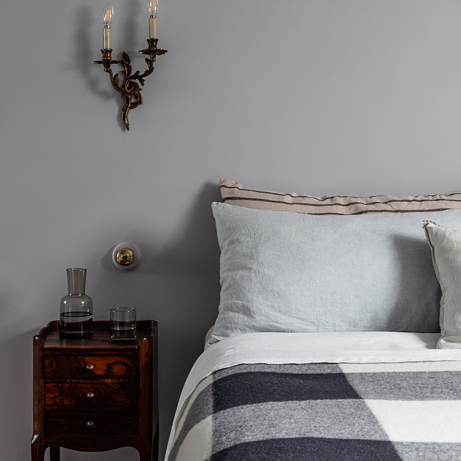 A bed made up with a Smiths Lane blanket in charcoal check.
