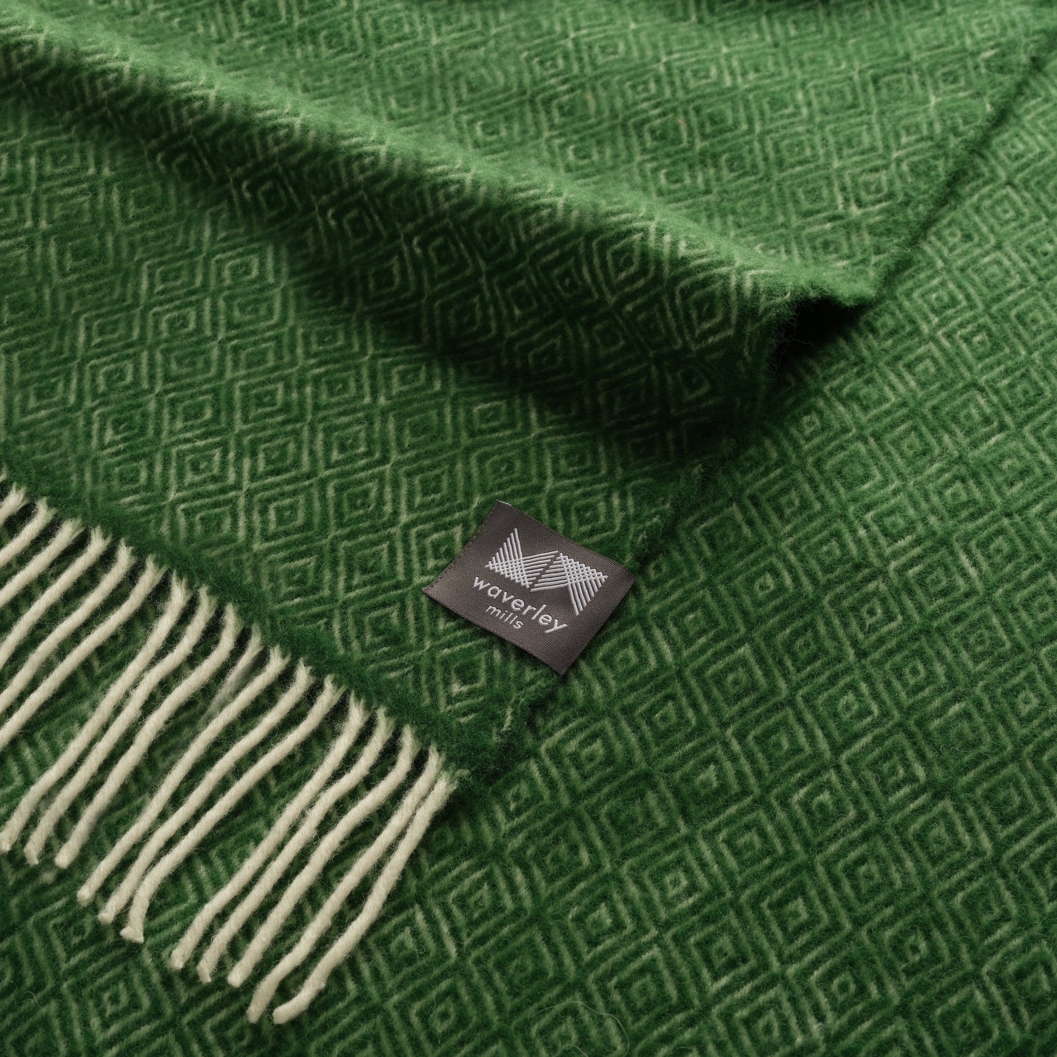 A close up of an artichoke green throw with a diamond pattern.