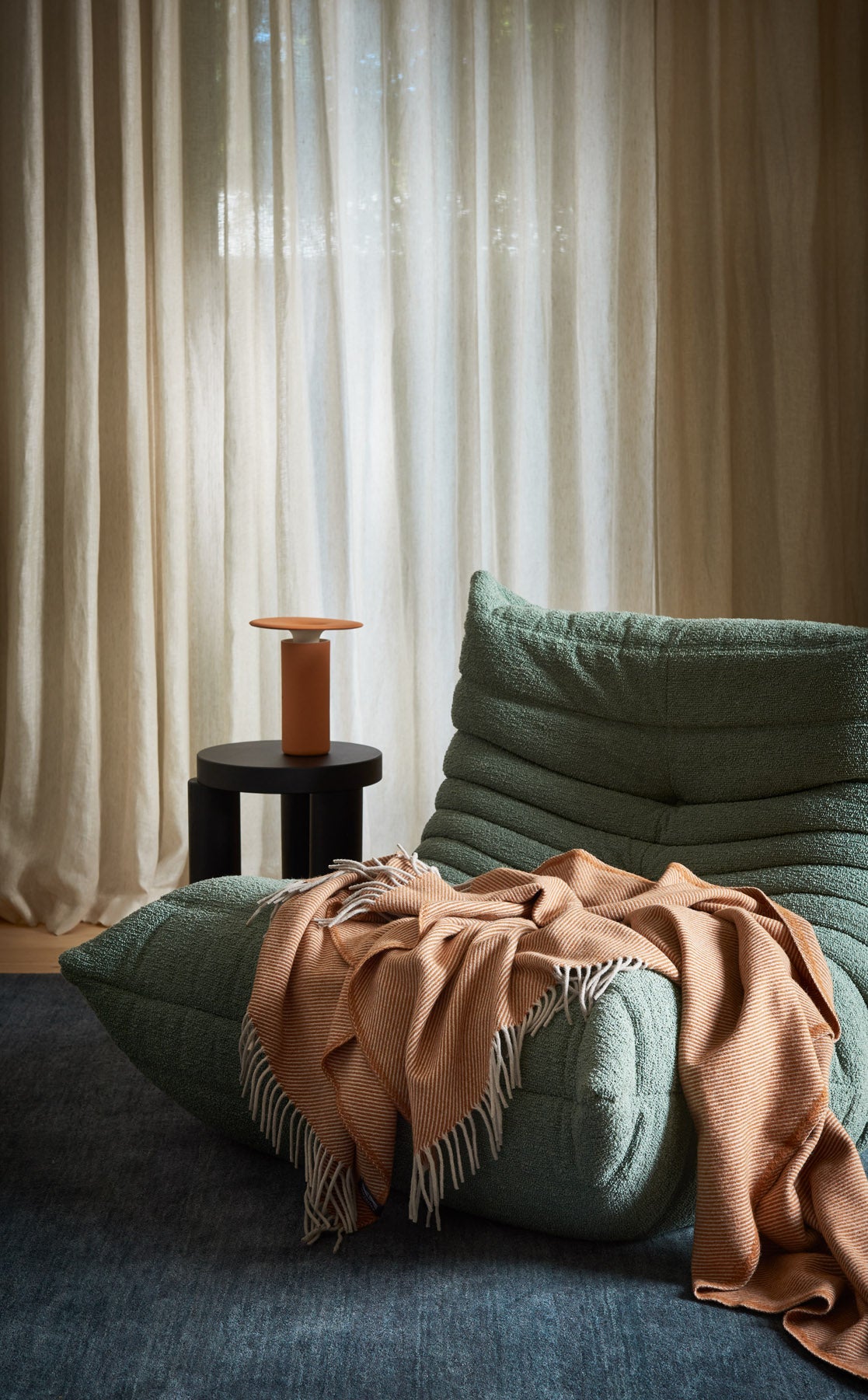 A togo arm chair with a diagonal throw draped over it.