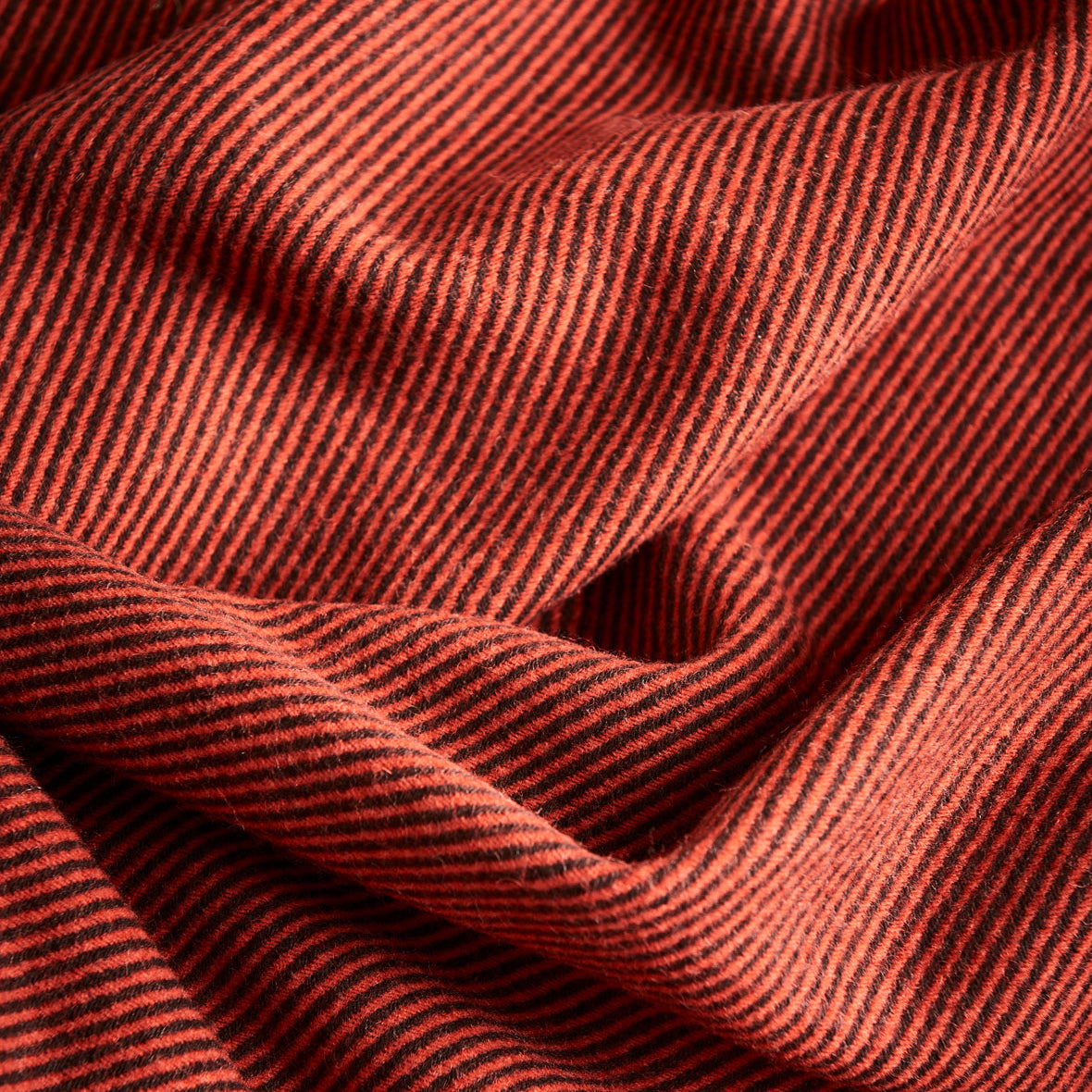 A close up of a diagonal throw in umber showing the drape of the fabric.