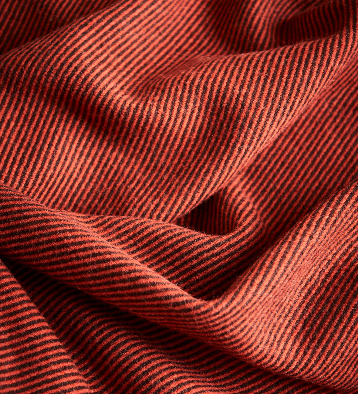 A close up of a diagonal throw in umber showing the drape of the fabric.