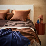 A modern styled bed made up with a geo blanket in umber and gem throw in cobalt.