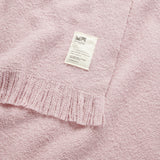 A close up of a cooper's cormo throw in mauve.