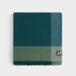 Folded pure wool graze picnic rug in green and blue.