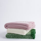 Three cooper's cormo throws, one in each colour, in a stack.