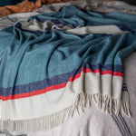 A Riviera throw in Mari blue draped over the end of a bed.