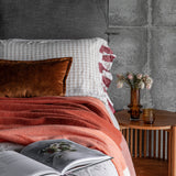A Sol throw in chutney and emberglow draped over a bed.