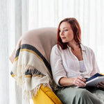 A woman sitting in a chair with a Riviera throw in shell draped over the back.