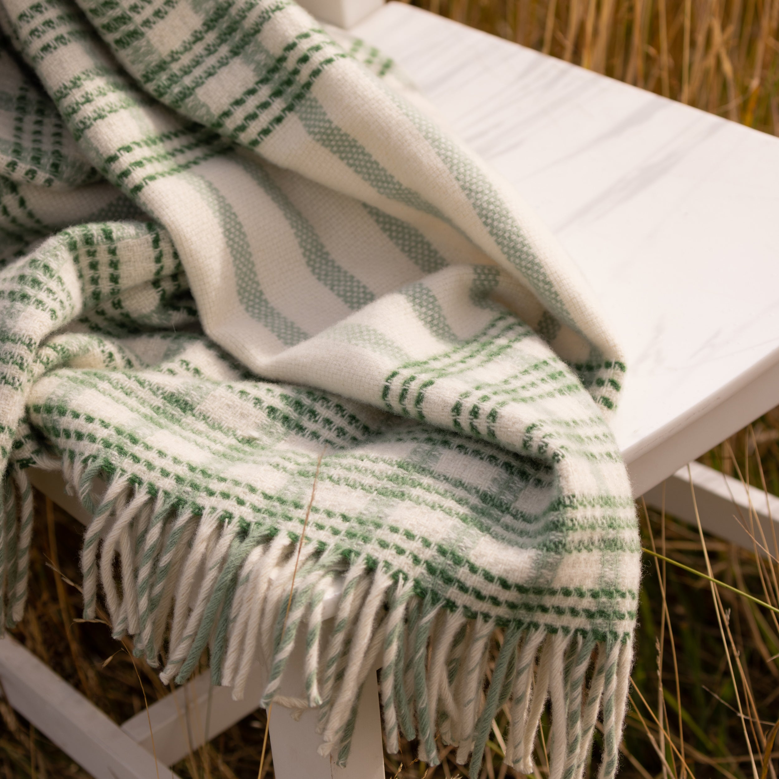 A wicker throw in greens draped over a chair.