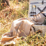 A picnic basket draped with a modern heritage throw in tan.