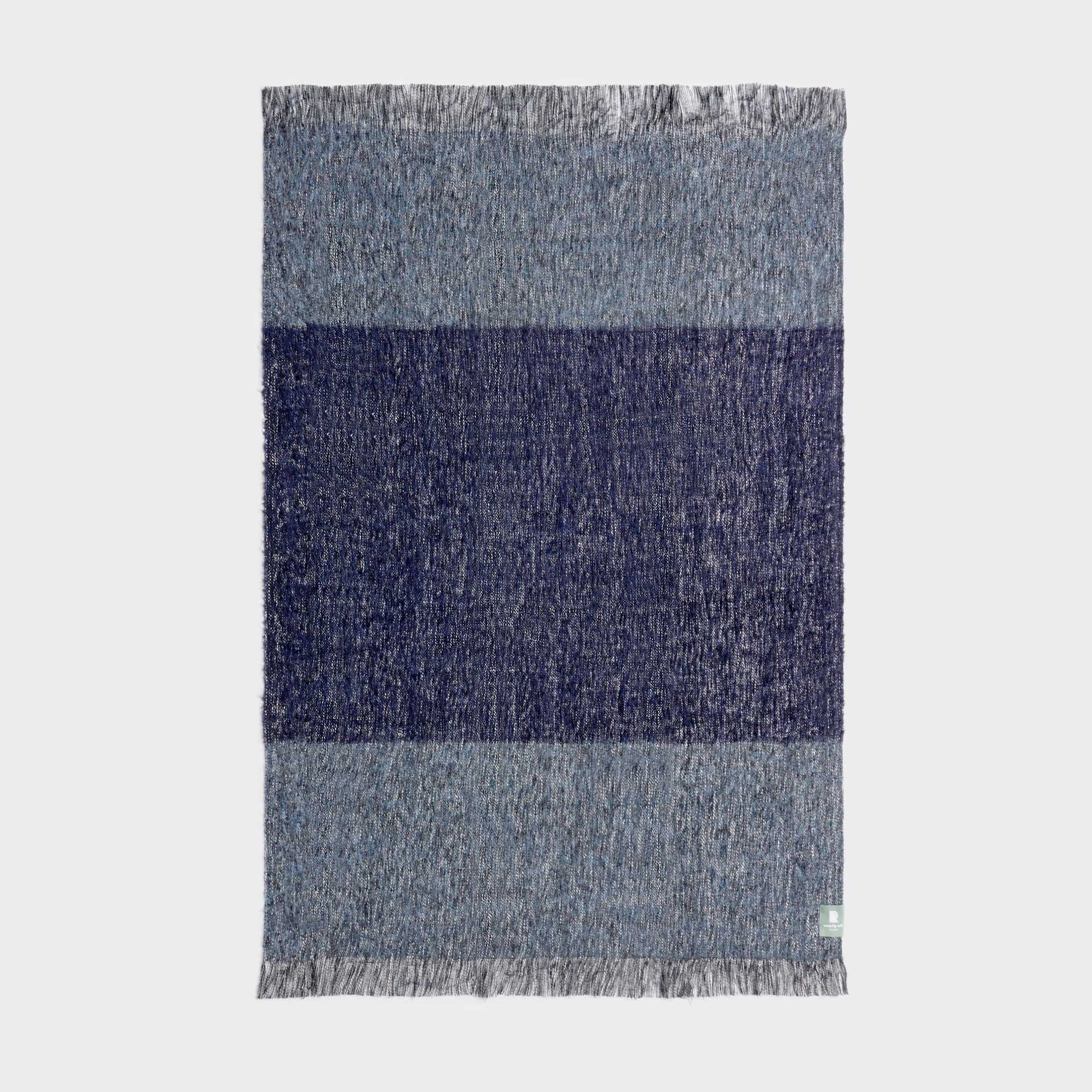 Full view of midnight blue fringe throw showing bold stripe pattern.