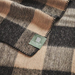 Close up of a kingsway travel rug in beige and black check.