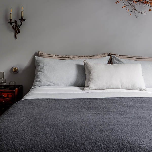 A vintage style bed dressed in a charcoal wellington blanket.