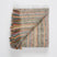 Folded multicolour alpaca throw showing stripes of alternating colour.