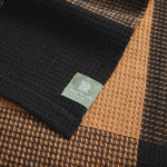Close up of brickfields travel rug in black and sahara showing waffle texture.