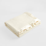Folded natural merino wool nursery blanket with satin edge.
