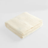 Folded waffle cot blanket in natural.