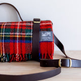 Close up of brown leather carrier securing a Royal Stewart tartan picnic rug.