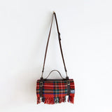 A leather carrier and shoulder strap holding a Royal Stewart tartan rug.